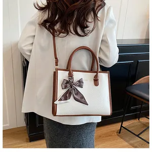 Détail montrant la texture cuir blanc serpent et la bandoulière marron avec foulard