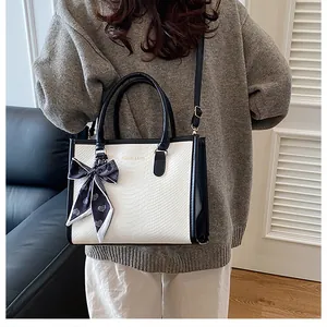 Modèle portant un sac à main crème effet serpent avec bordure noire et foulard en soie