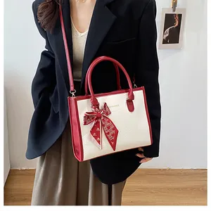 Détail du sac à main bicolore rouge et blanc avec texture crocodile et foulard en soie