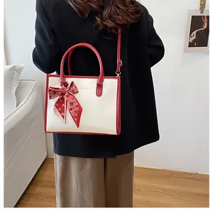Détail du sac à main bicolore rouge et blanc avec texture serpent et nœud en soie