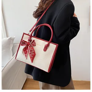Détail d'un sac à main bicolore avec foulard en soie et lettrage doré de mode