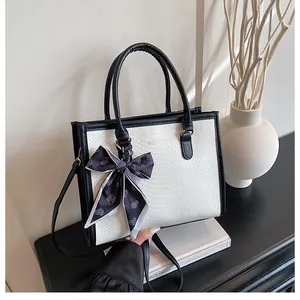 Détail du sac à main bicolore avec texture serpent et accessoire foulard en soie élégant