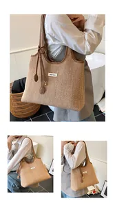 Detailed view of woven straw tote bag with brown leather handles and brand logo tag
