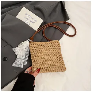 Détail du sac bandoulière en paille avec dentelle blanche et pompons en perles