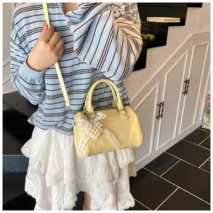 Detail of light yellow Boston bag with pearl bow charm and delicate lychee texture