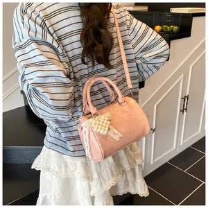 Detail of light pink mini Boston bag with pearl heart pendant and lace bow charm