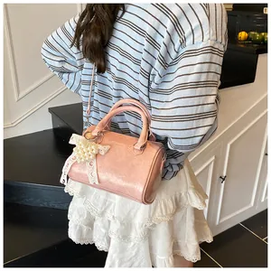 Detail of pink Boston bag featuring pearl fruit charm and delicate lace bow accent