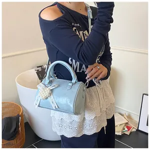 Detail view of light blue Boston bag with glossy texture and lace pearl heart pendant