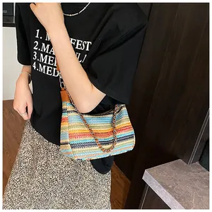 Close-up of rainbow striped straw tote bag with chain strap and summer resort vibes