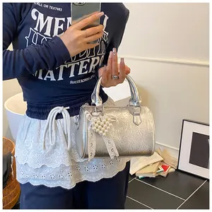 Detail of silver metallic Boston bag with heart pearl charm and lace bow decoration