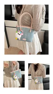 Détail du sac à main en denim bleu avec bordure en cuir rose et breloque peluche blanche