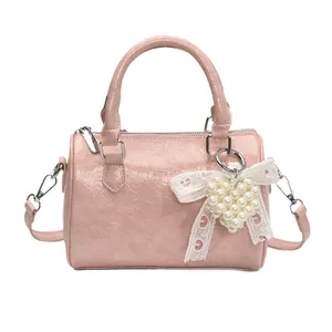 Pink Boston handbag with glossy wrinkled texture and pearl heart charm accessory