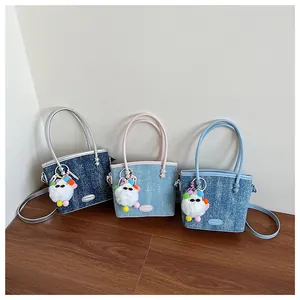 Vue détaillée des sacs seaux en patchwork de denim avec breloques en peluche et cuir