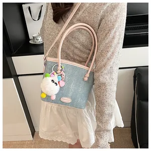 Détail du sac seau bleu clair pailleté avec anse rose et breloque peluche dessin animé