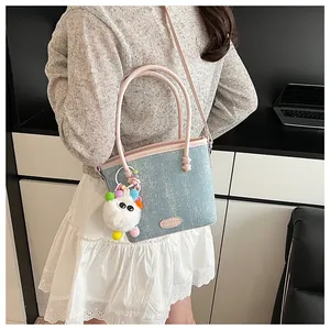 Détail montrant la texture denim bleue, les poignées roses et le charm monstre en peluche