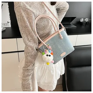 Gros plan du sac cabas texturé bleu clair avec anses roses et breloque monstre