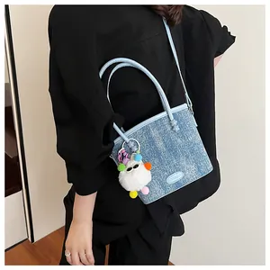 Détail d'un sac à main bleu clair en denim avec un charmant pendentif en peluche coloré