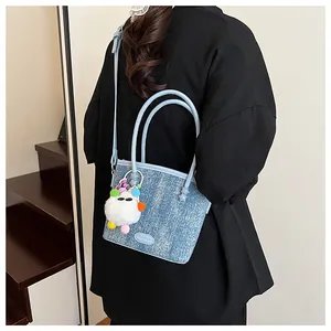 Détail du sac seau en denim bleu clair avec charm monstre en peluche coloré