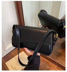 Détail du sac selle noir avec rabat ondulé, similicuir lisse et anneau en D doré brillant