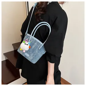 Détail du sac à main en jean bleu clair avec breloque en peluche douce sur la bandoulière