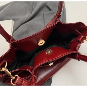 Detailopname van bordeauxrode oliewas tas met gouden magneetsluiting en voering