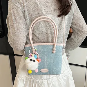 Mini sac cabas en jean avec poignées roses et pendentif en peluche porté par le mannequin