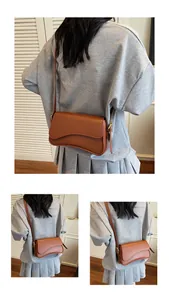 Détail d'un sac besace en cuir marron avec rabat ondulé et boucles dorées