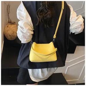 Détail d'un sac à main jaune en cuir grainé avec bandoulière porté par un mannequin