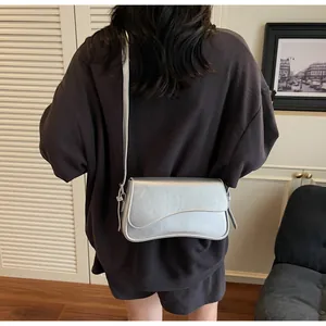 Détail du sac selle argenté avec rabat asymétrique et finition nacrée brillante chic