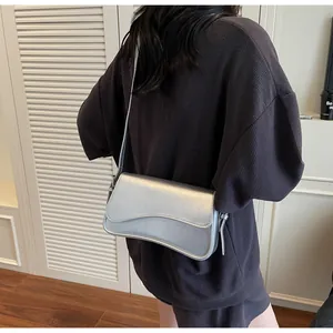 Gros plan d'un sac besace argenté métallisé avec rabat magnétique et fine bandoulière