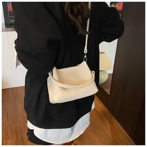 Gros plan d'un sac bandoulière blanc cassé avec texture litchi et lettrage stylé