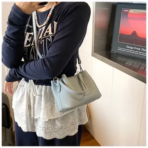 Détail du sac seau en cuir texturé bleu clair avec texte porté par le mannequin