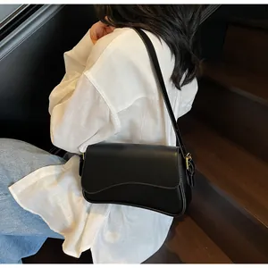Détail d'un sac bandoulière noir avec rabat ondulé et boucle en métal doré