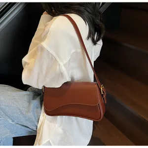Détail du sac à bandoulière vintage marron avec rabat ondulé et boucle dorée chic