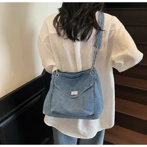 Vue de dos d'un mannequin portant un sac à bandoulière en denim bleu délavé avec fermoir métal.