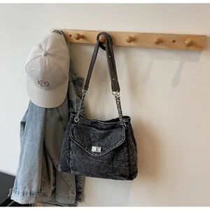 Retro washed denim shoulder bag hanging on a wooden rack with a cap and jacket.