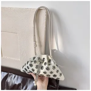 Detail of cream bucket bag featuring silver grommets, chain drawstring and pearl charm
