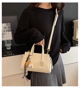 Detail of cream-white handbag with baseball theme charm and gold-tone hardware accents