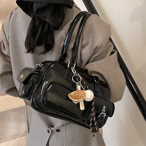 Glossy black bowling handbag with silver hardware and sports charms on a model