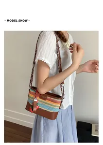 Modell mit farbenfroher gewebter Eimertasche mit Lederriemen und Erdbeeranhänger