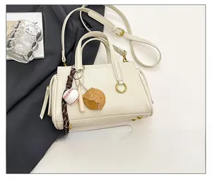 Detailed view of cream white leather shoulder bag with baseball charm and size reference