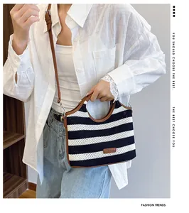 Detailed close-up of a striped woven tote bag with brown leather trim and shoulder strap