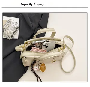 Beige leather handbag showing inner capacity with phone, card holder and baseball charm