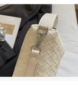 Gros plan du sac en cuir tressé beige montrant les détails en métal argenté