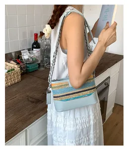 Detailierte Textur der bunten Strohtasche mit blauem Lederbesatz und silberner Kette