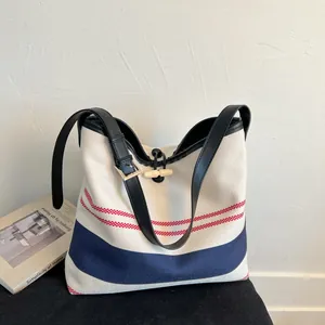 Close-up of a striped canvas tote bag with leather strap in a minimalist setting