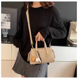 Detail of beige Boston bag with baseball charms and golden circular metal hardware