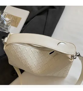 Gros plan d'un sac à main crème en cuir tressé avec motif Intrecciato et fermeture argentée