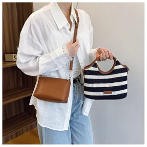 Detail of blue striped woven tote bag with brown leather handles and a leather crossbody bag