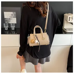 Beige PU leather handbag with baseball charm and thin shoulder strap shown in lifestyle view